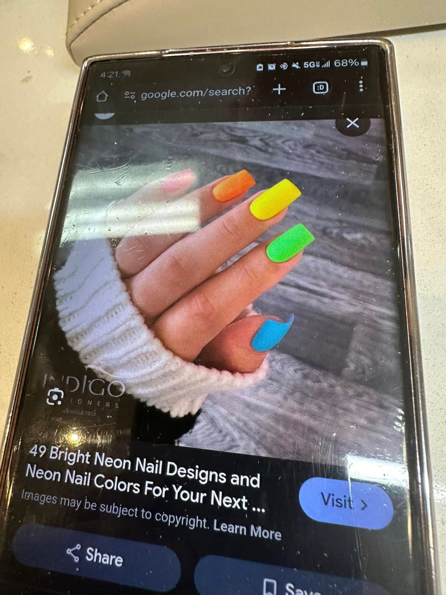 A phone screen displaying a web search for neon nail designs showing hand with orange, yellow, green, and blue nails.