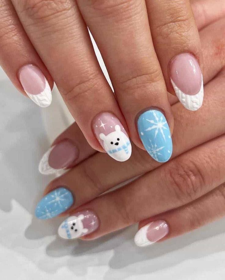 Manicured nails featuring a winter theme with cable-knit French tips, baby blue snowflake patterns, and polar bear art.