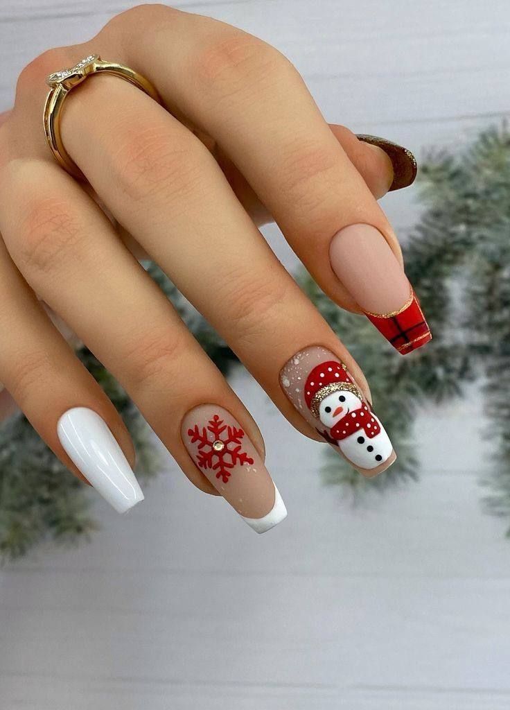 A hand displays holiday-themed coffin-shaped nails with a white, red snowflake, snowman, and plaid French tip design.