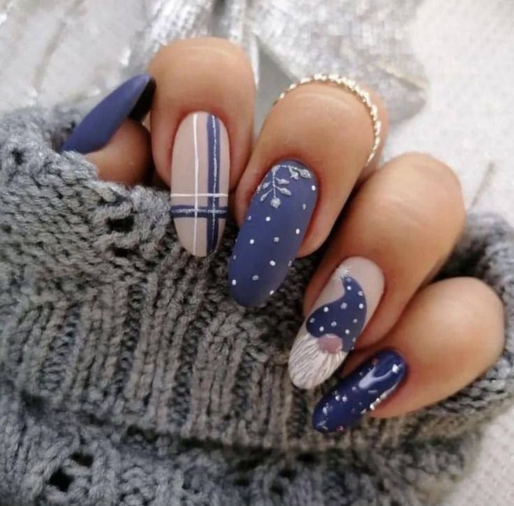 Manicured fingernails with matte navy and nude polish featuring plaid patterns, white polka dots, and a gnome illustration.