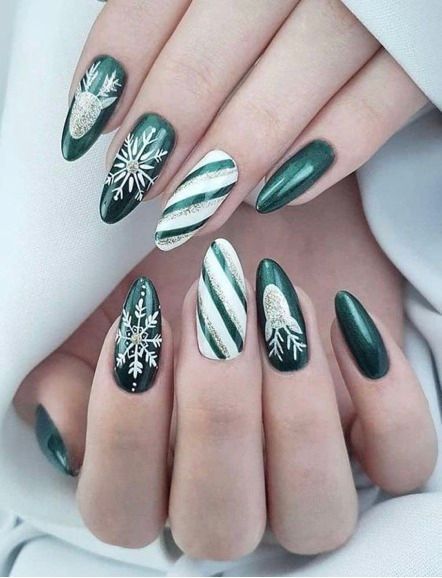 Almond-shaped nails painted deep green, featuring silver snowflake, reindeer, and diagonal stripe accents.