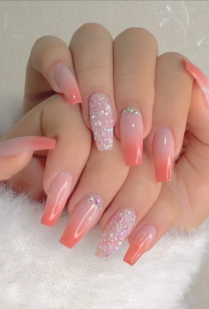 Coffin-shaped nails featuring a coral-to-nude ombre fade, accented with silver glitter, rhinestones, and full glitter nails.