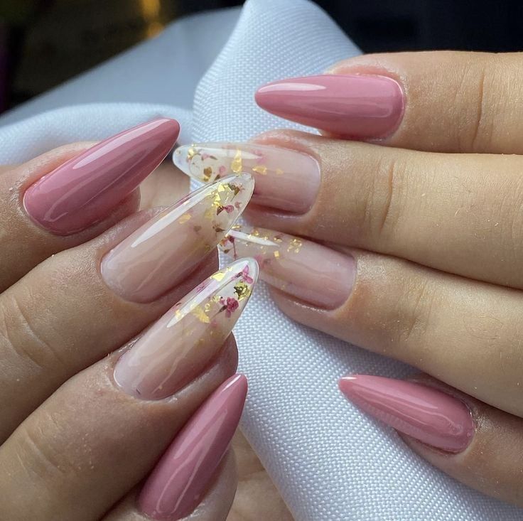 Long, almond-shaped nails with a mix of solid dusty rose polish and sheer tips accented with gold foil and dried flowers.