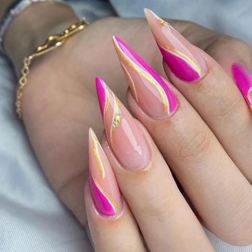 Sharp, stiletto-shaped nails featuring a nude base, vibrant magenta tips, and elegant gold swirl accents.