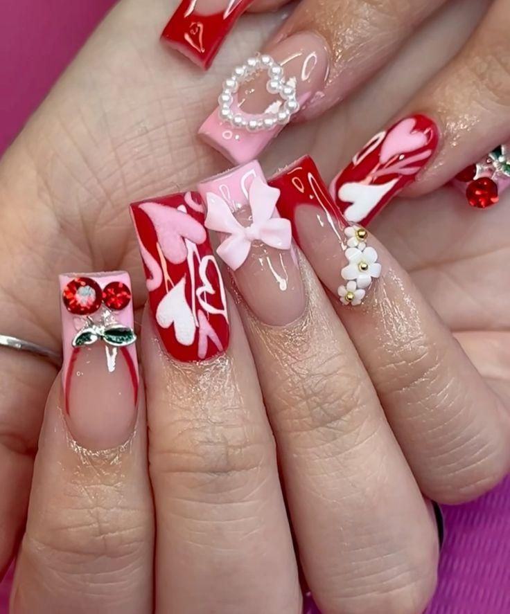 Long, square-shaped acrylic nails decorated with pink and red heart patterns, 3D bows, pearls, flowers, and rhinestones.