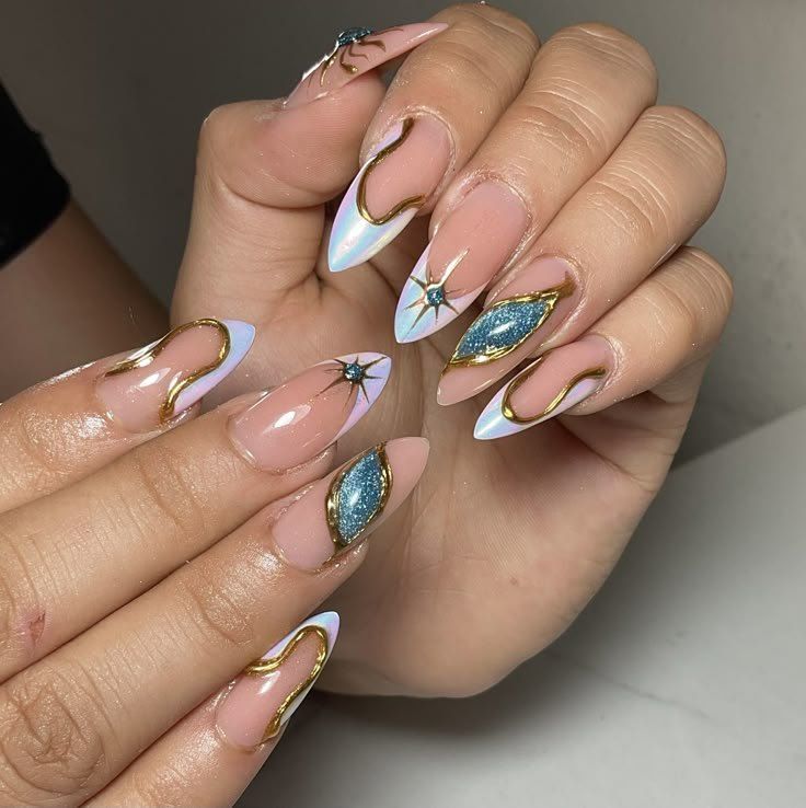Almond-shaped nails featuring blue glitter accents, metallic gold detailing, and star designs on a nude base.