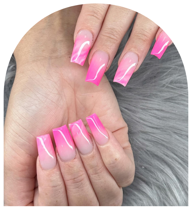A hand displays square-shaped acrylic nails with a bright pink-to-nude gradient design against a soft gray fur background.