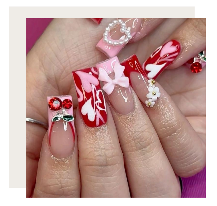 Manicured nails featuring pink and red heart patterns, 3D bows, pearl heart charms, flower studs, and crystal accents.