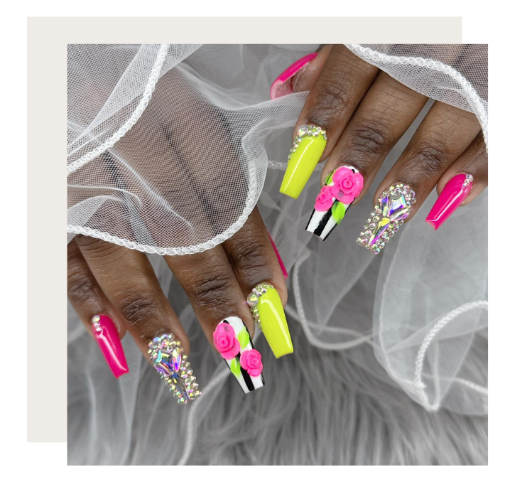 Hands display elaborate coffin-shaped nails featuring bright neon yellow and pink polish, 3D floral art, and rhinestones.