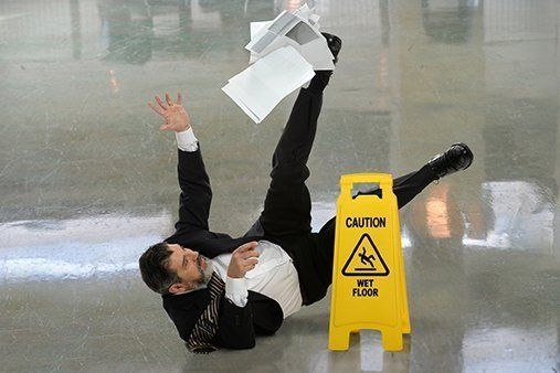 A man is falling on a wet floor next to a caution sign