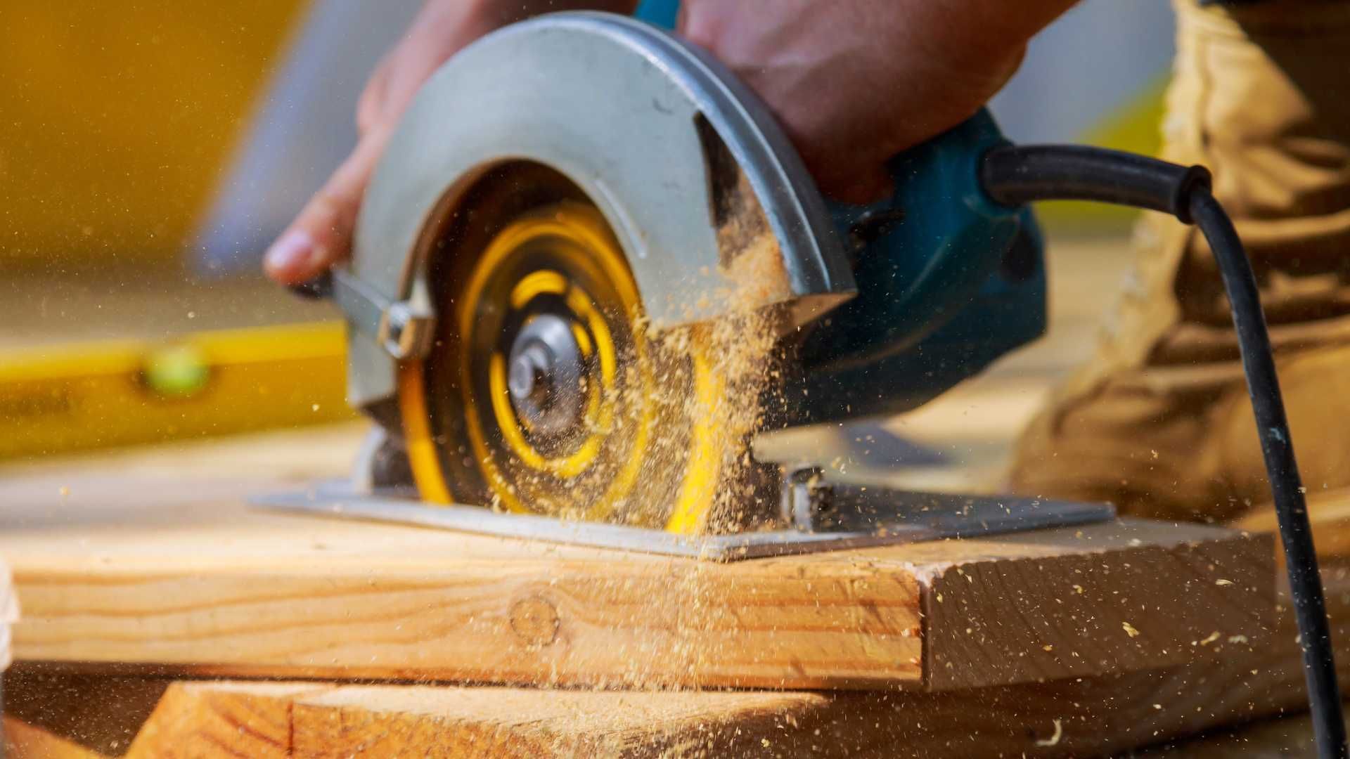 A person is using a circular saw to cut a piece of wood.