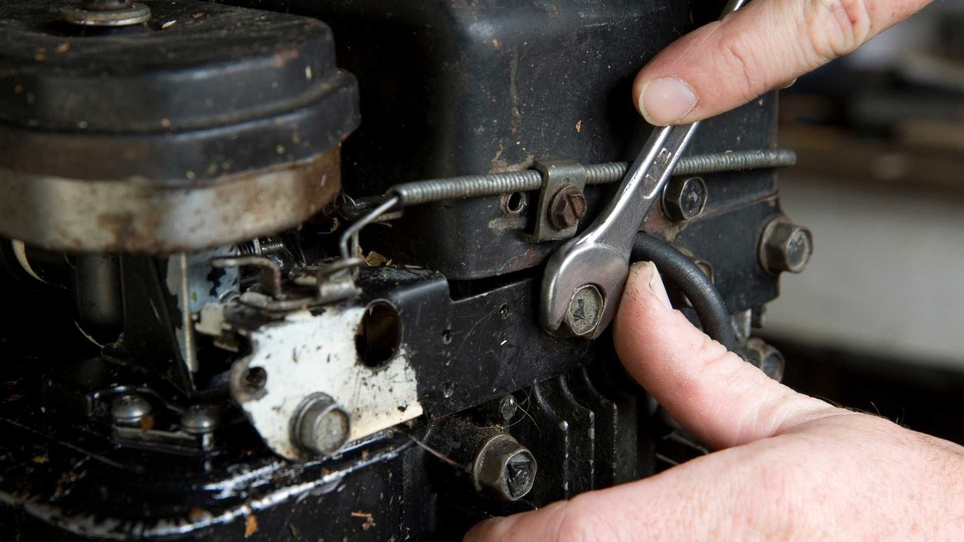 A person is fixing a motor with a wrench.