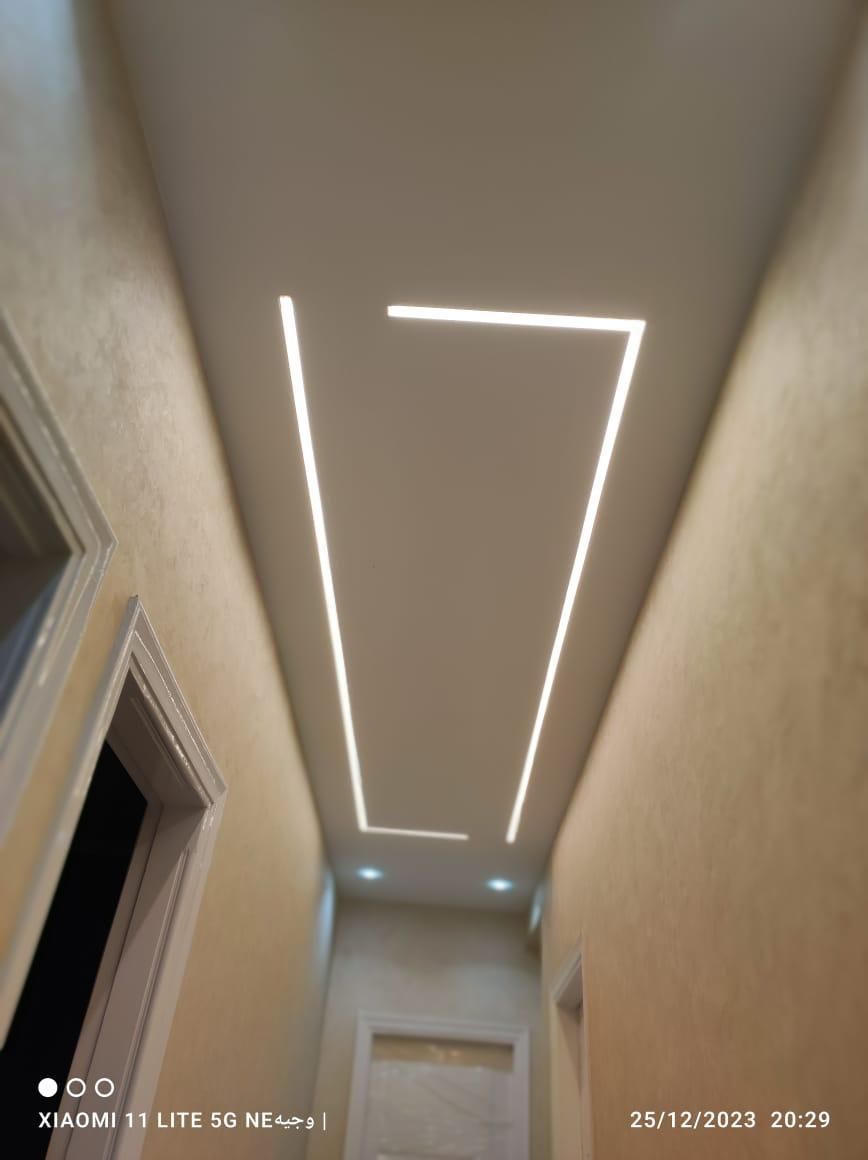 Un corridoio con controsoffitto incassato e luci LED lineari. Le pareti sono beige.