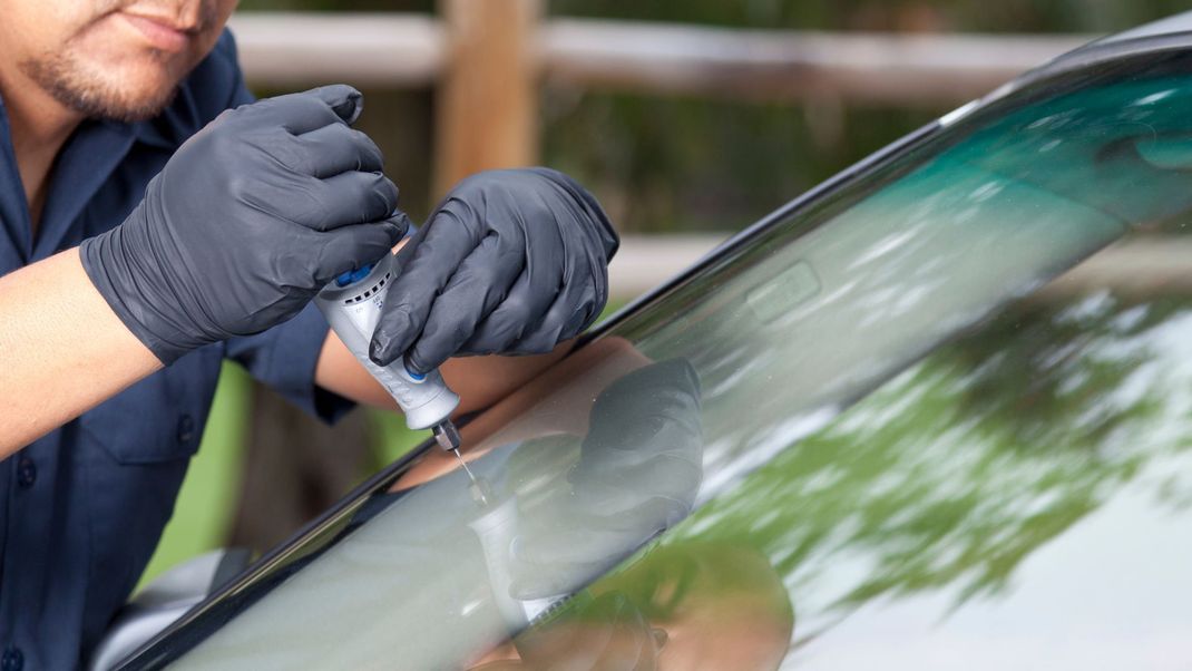 a man is repairing a windshield on a car .