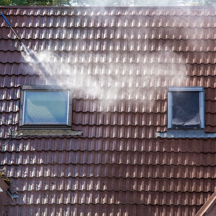 Smoke is coming out of a window on the roof of a house.