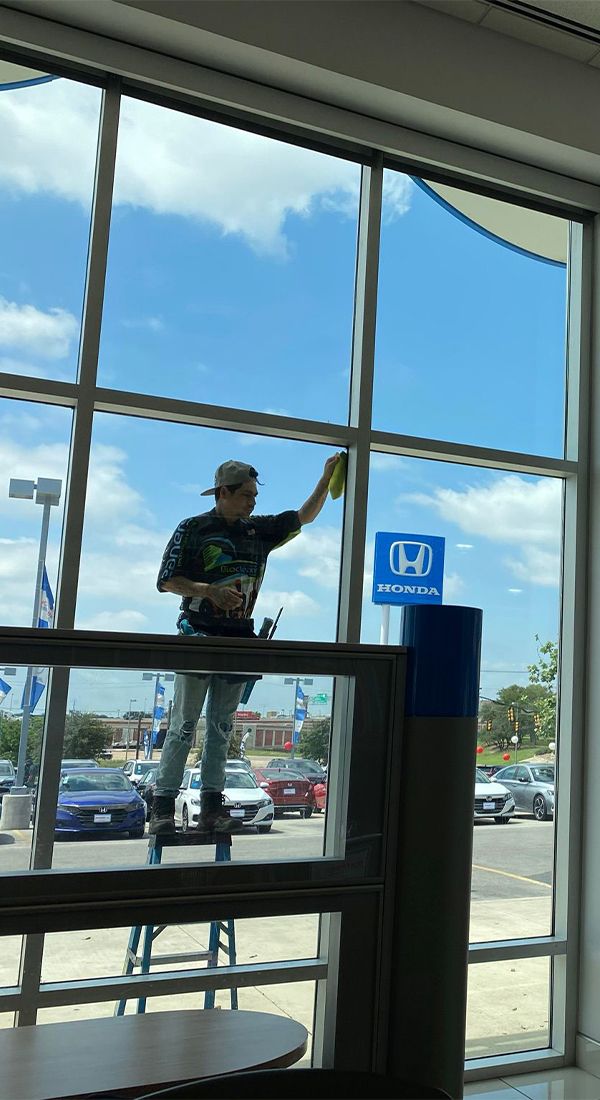 A man is standing on a ladder cleaning a window.
