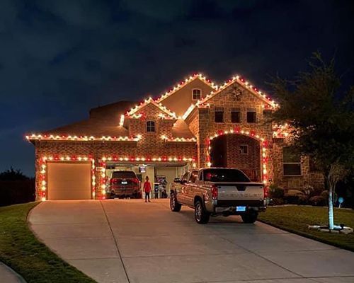 A truck is parked in front of a house decorated with christmas lights.