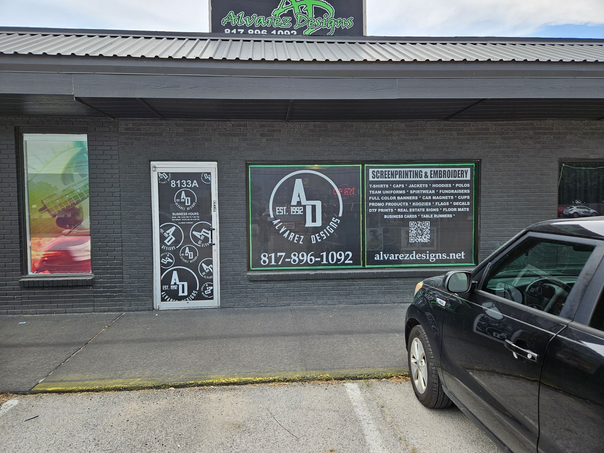 A black car is parked in front of a building.