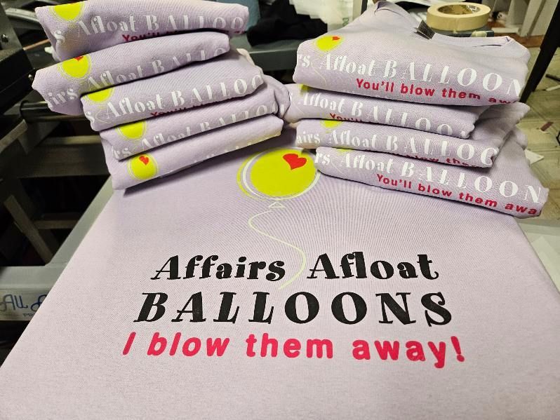 A stack of shirts that say affairs afloat balloons i blow them away