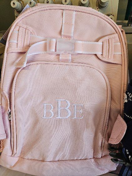 A pink backpack with the letters bb embroidered on it