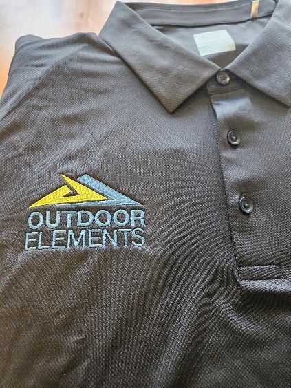 A black polo shirt with the words outdoor elements embroidered on it