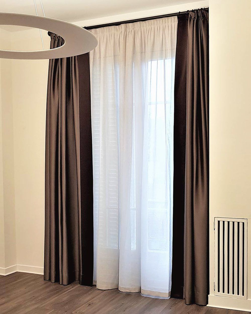Una stanza con tende marroni e tende bianche