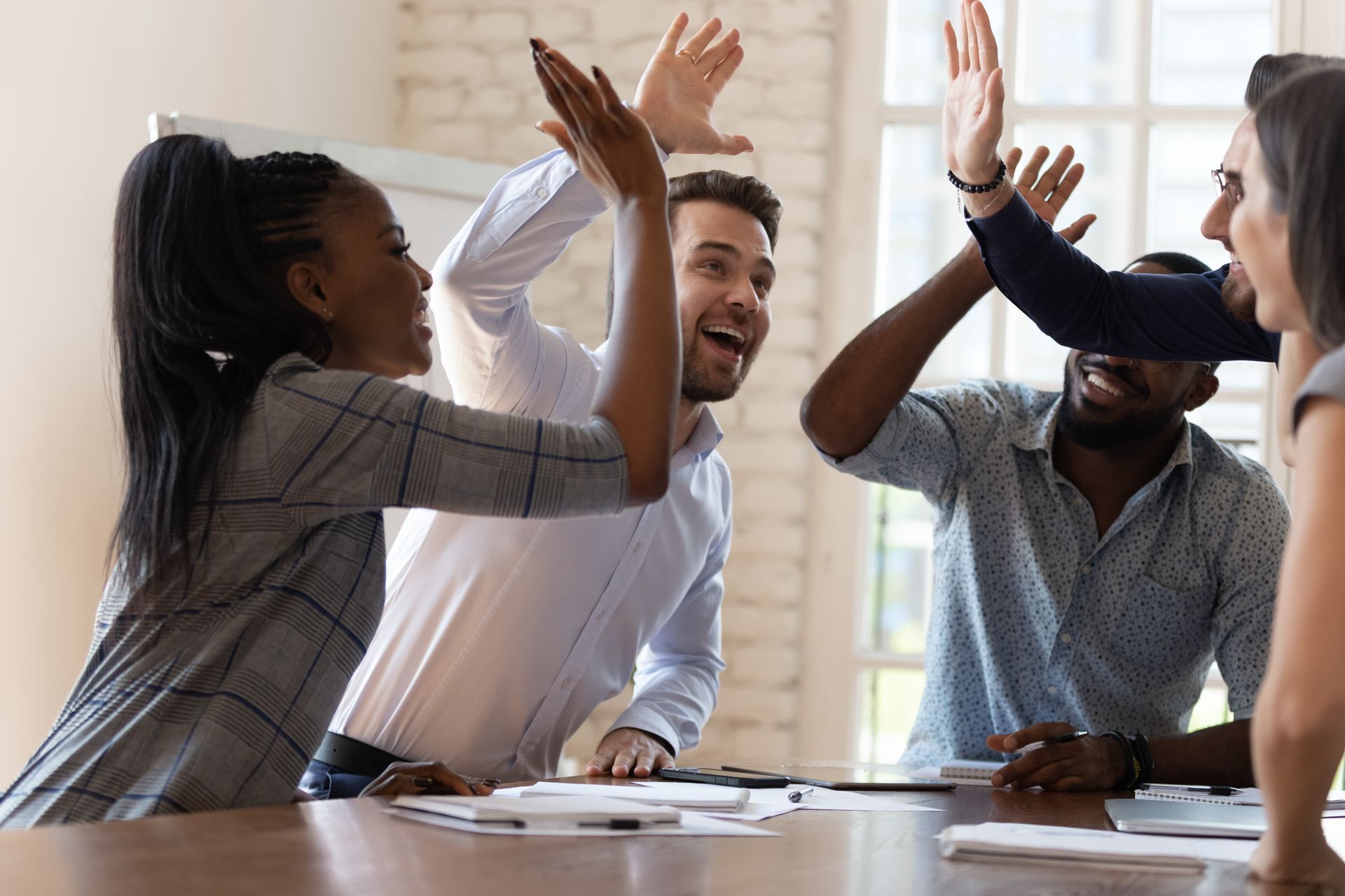 Team celebrates success with high fives at a meeting table