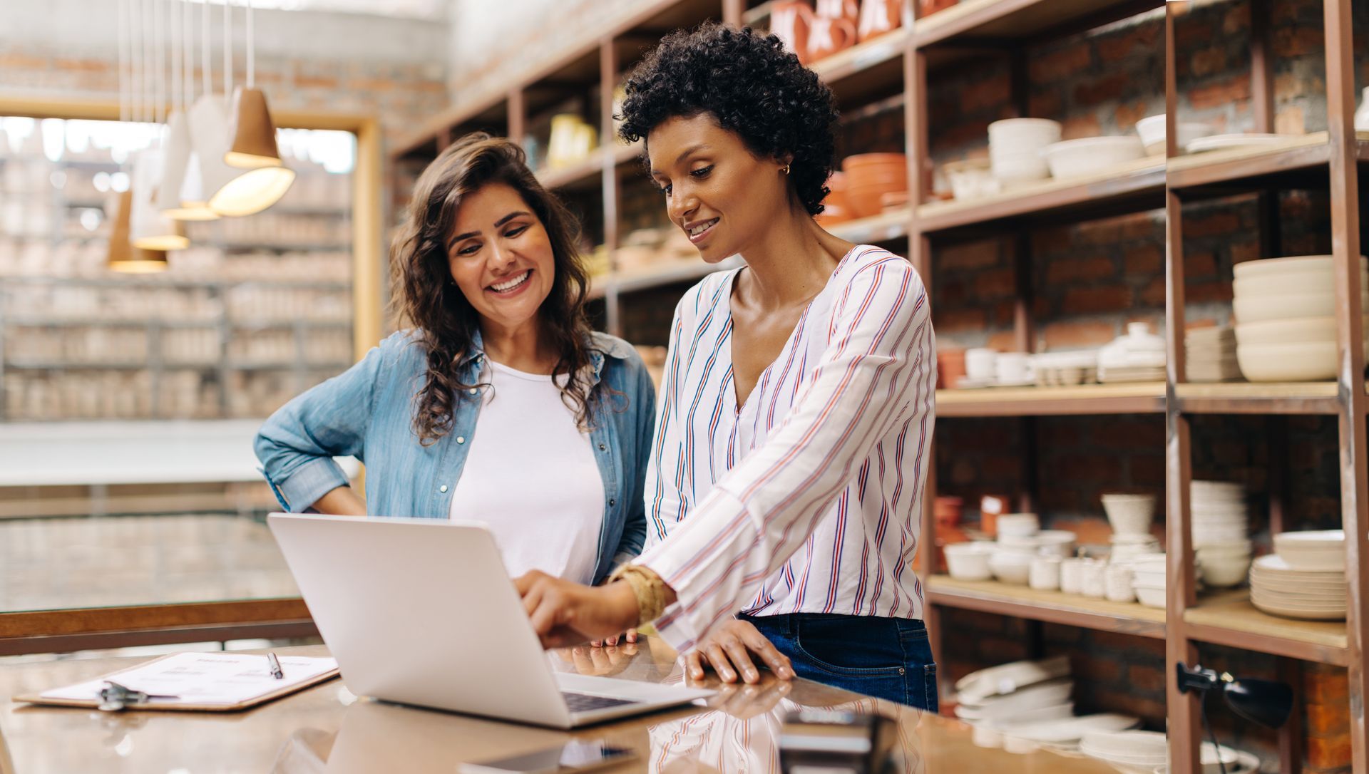 Two women looking at a laptop in a pottery shop