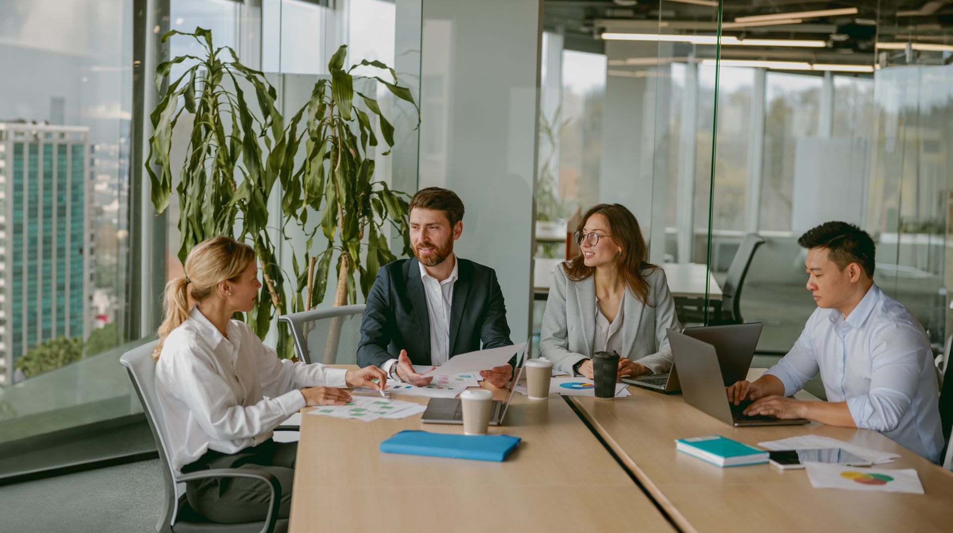 Four people in business attire at a meeting in a modern office