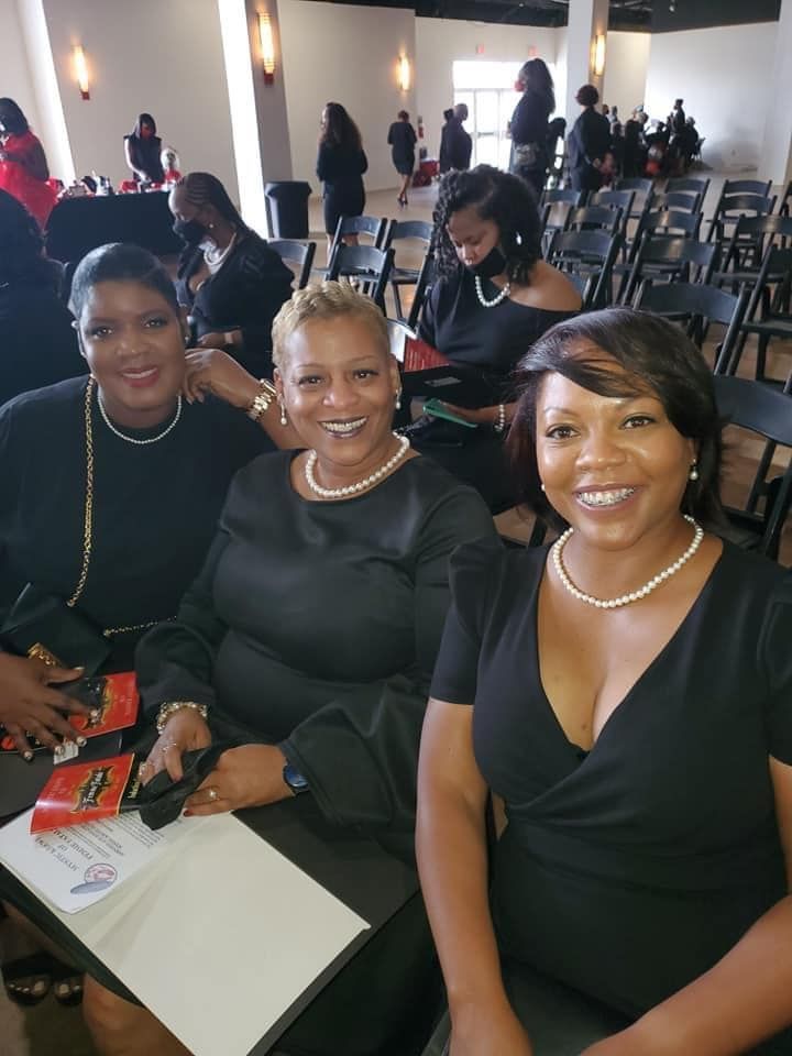 A group of women in black dresses are sitting in a room.