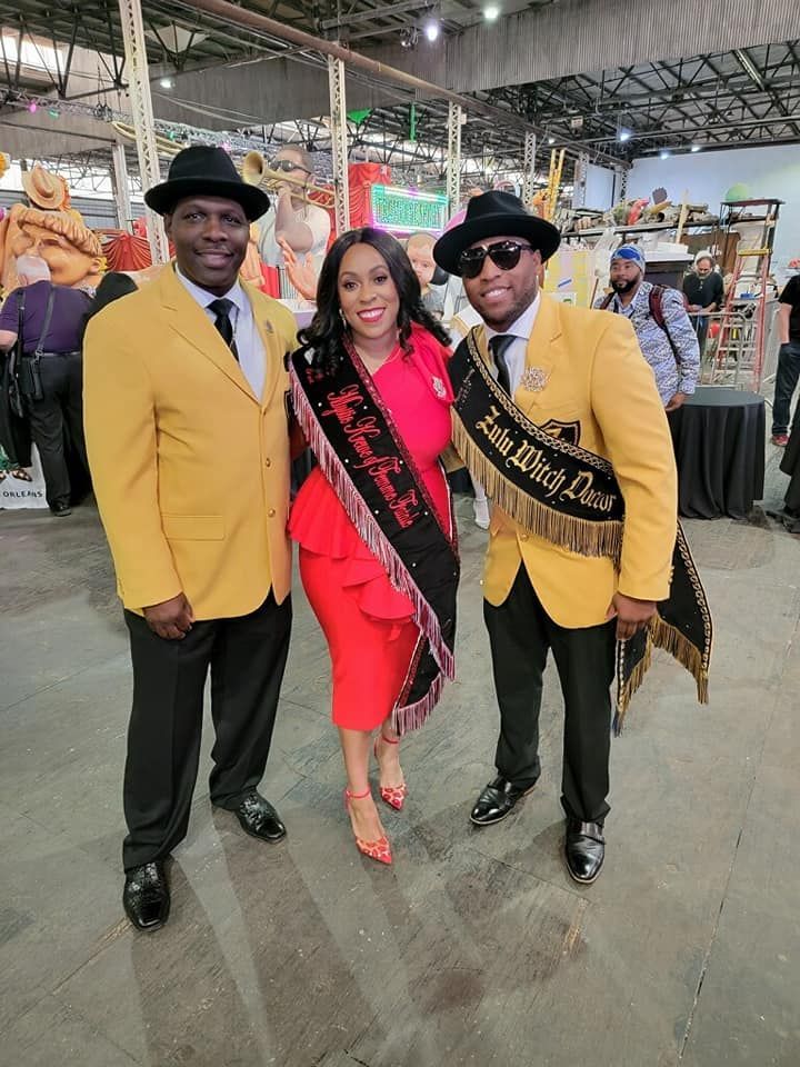 A woman in a red dress is posing for a picture with two men in yellow suits.