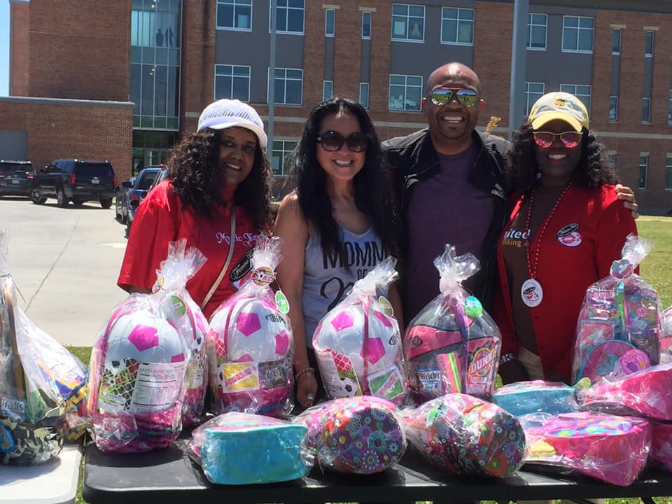 A group of people are posing for a picture in front of a table full of easter baskets.