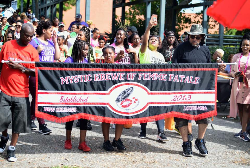 A group of people holding a banner that says mystic brewing of femme fatale