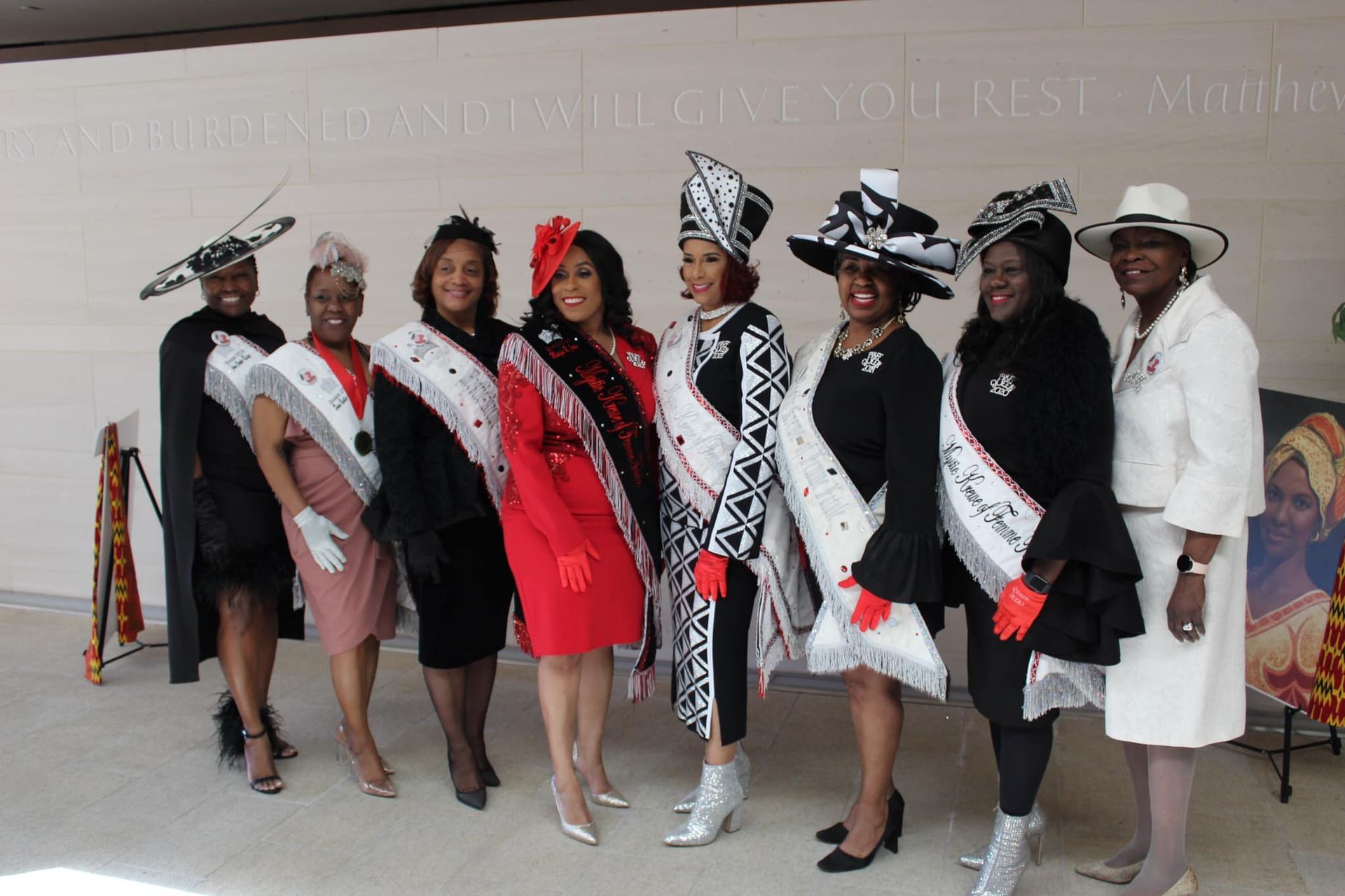 A group of women standing next to each other wearing hats and sashes