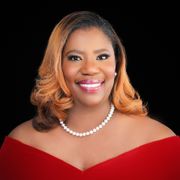 A woman wearing a red dress and a pearl necklace is smiling for the camera.