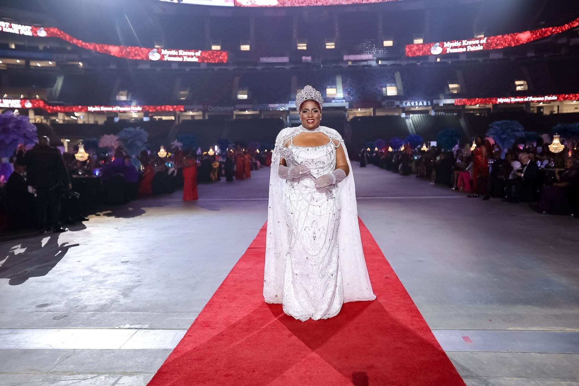 A woman in a white dress is wearing a tiara and holding a wand.
