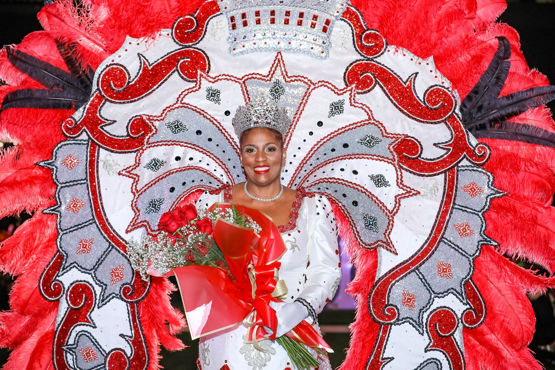 A woman in a white dress and gloves is wearing a tiara