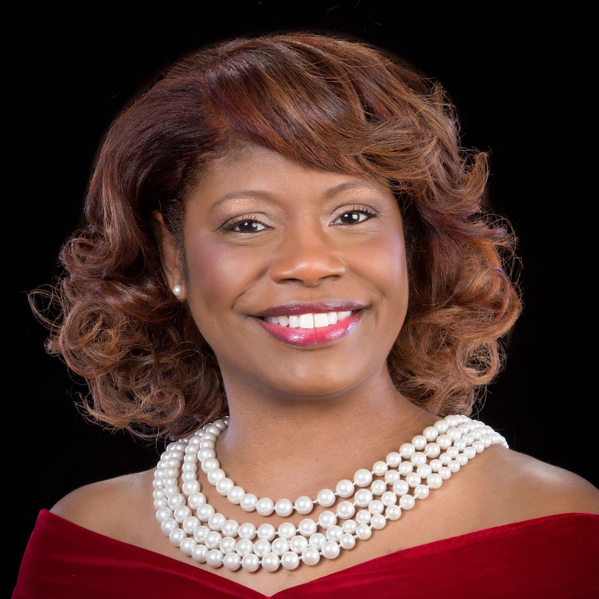 A woman is wearing a white fur coat and a pearl necklace.