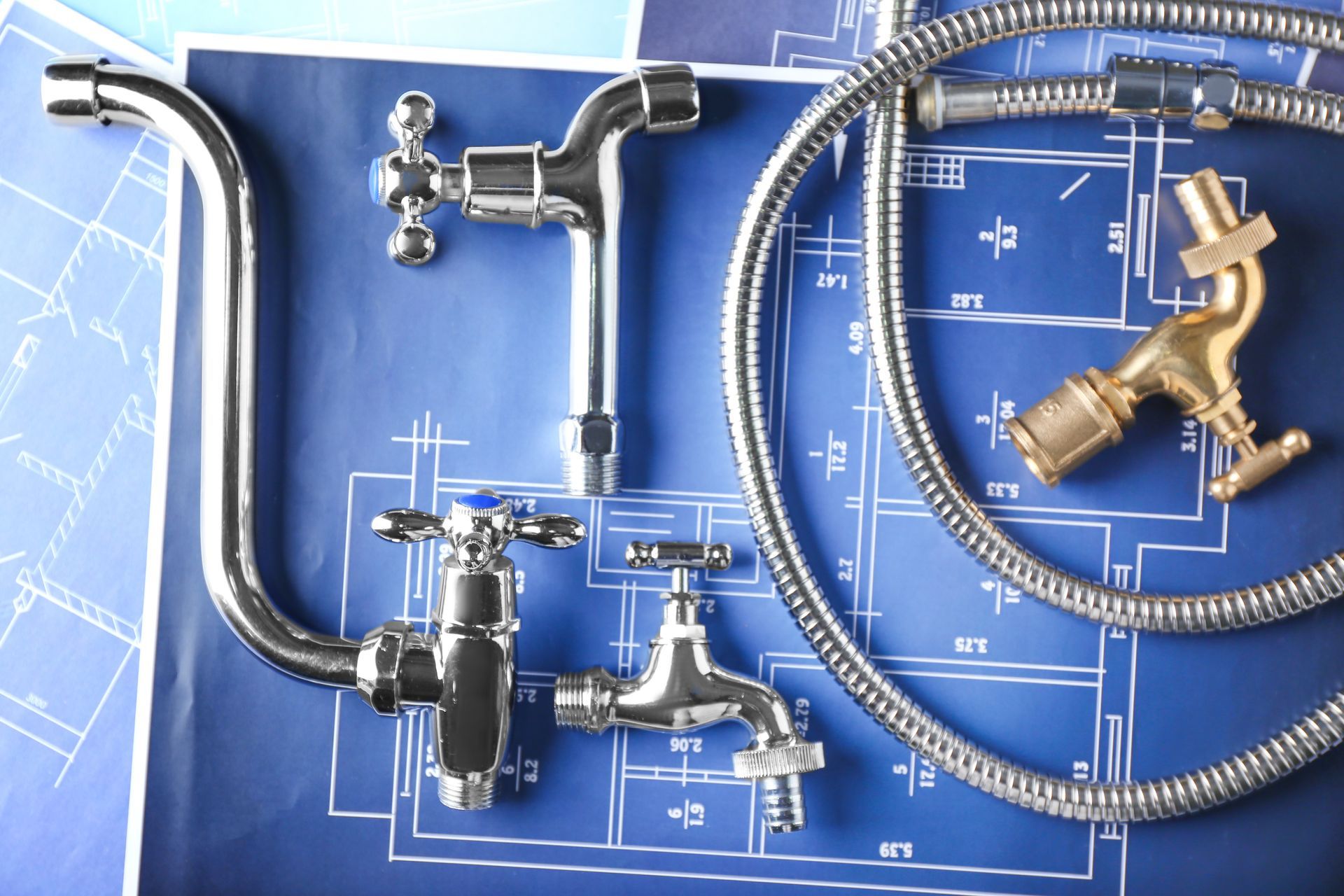 Appareils de plomberie : robinets chromés, flexible de douche et valve en laiton sur fond de plan bleu.