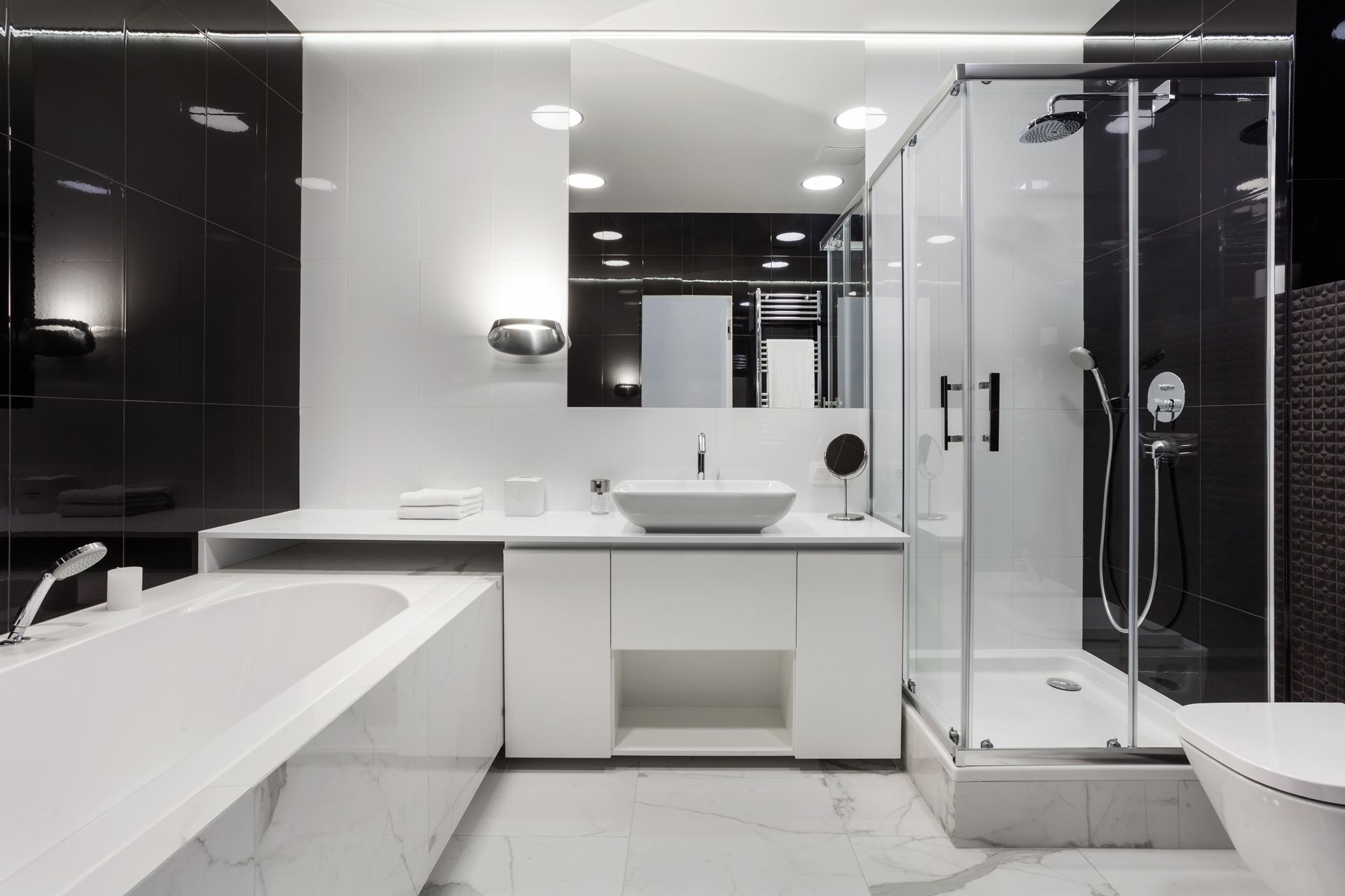 Salle de bain moderne noire et blanche avec baignoire, douche et lavabo.