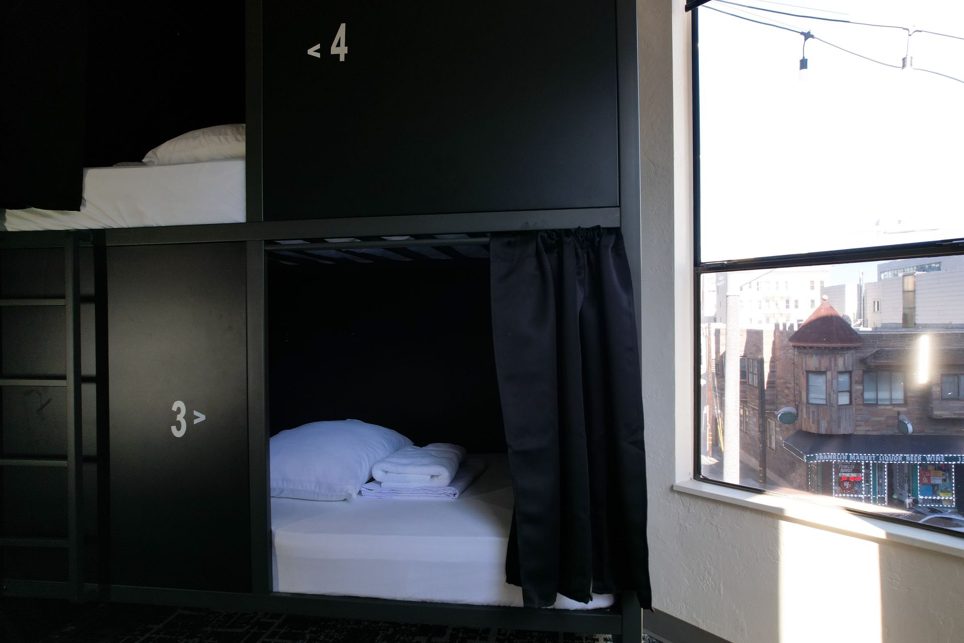 Bunk beds in a room with a window. The beds are black, and the room has natural light.
