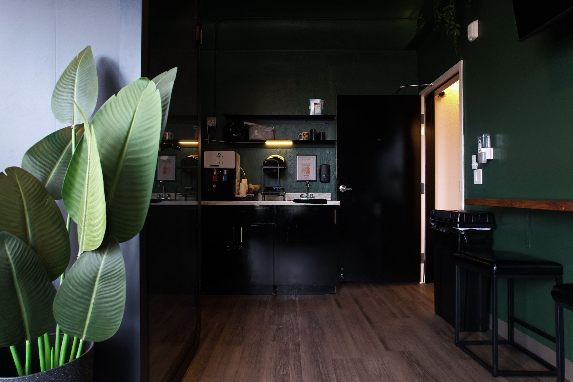 Office space with a dark green wall, refrigerator, and doorway to a hallway.