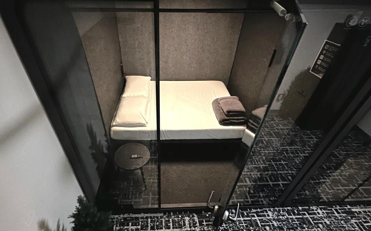 Bedroom with white sheets, pillows, and towels on a bed. Dark gray walls.