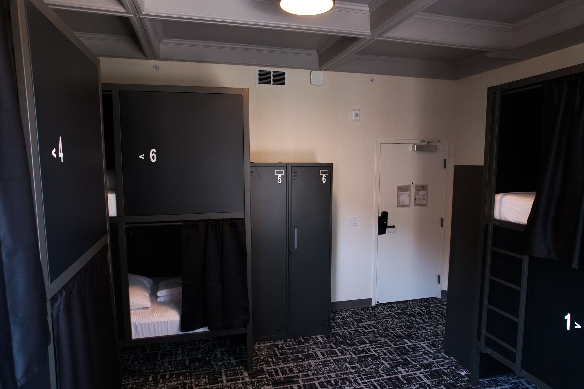 Dorm room with bunk beds, a wardrobe, and a patterned rug.