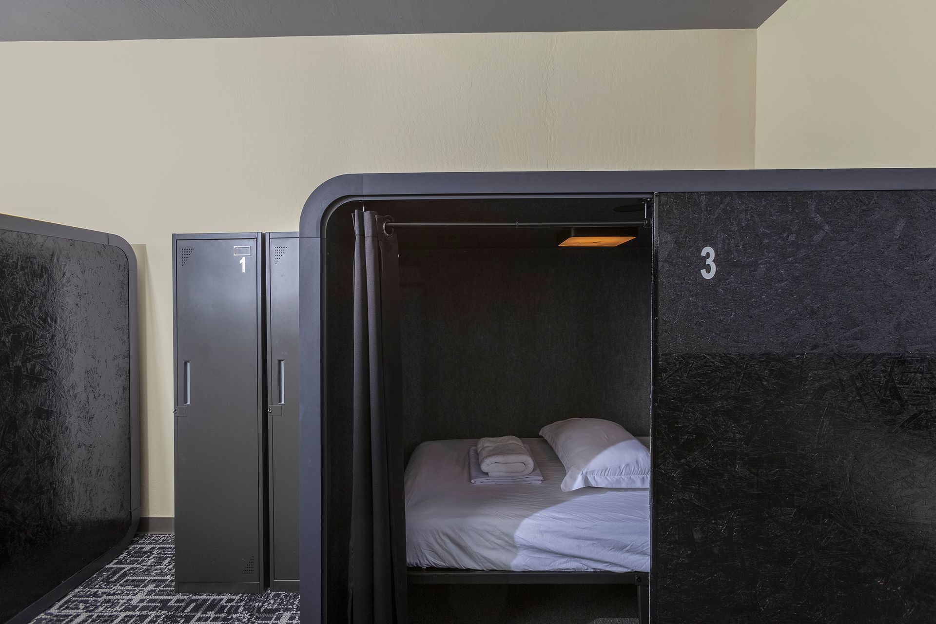 Bedroom with white sheets, pillows, and towels on a bed. Dark gray walls.