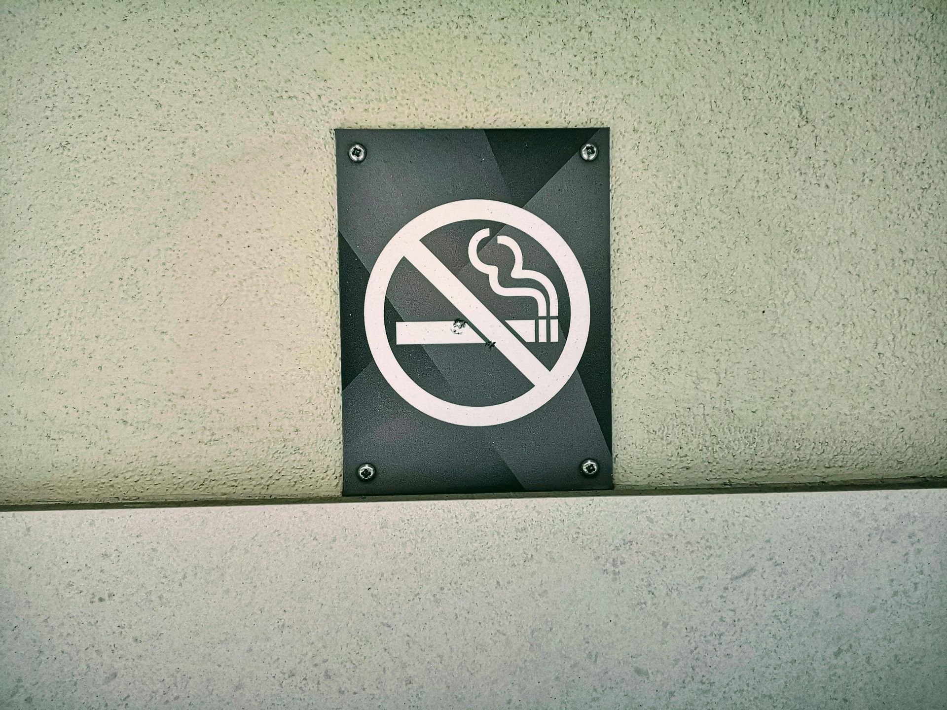 No smoking sign on a wall, white symbol on a dark gray background.