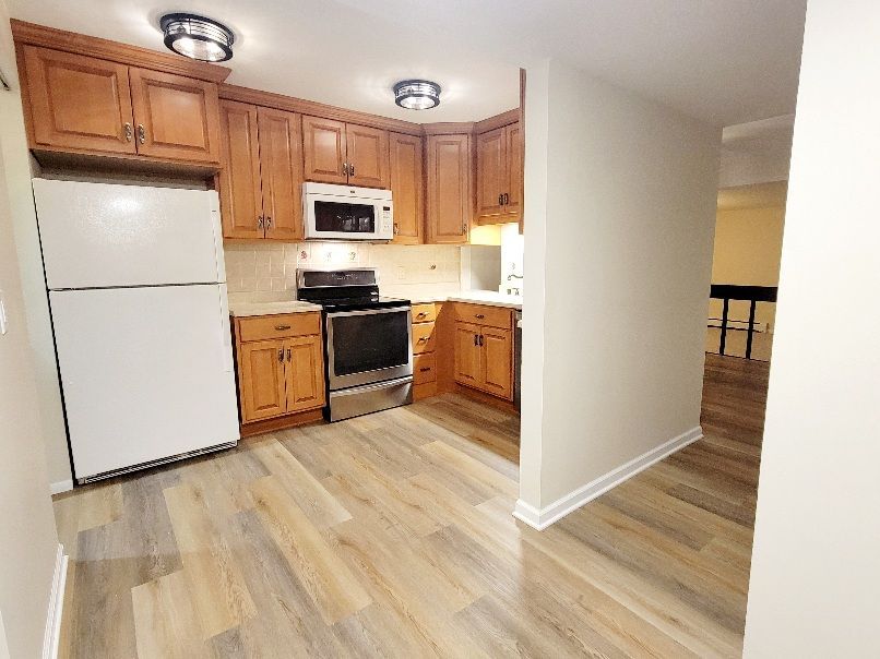 A kitchen with wooden cabinets , stainless steel appliances , and a refrigerator.