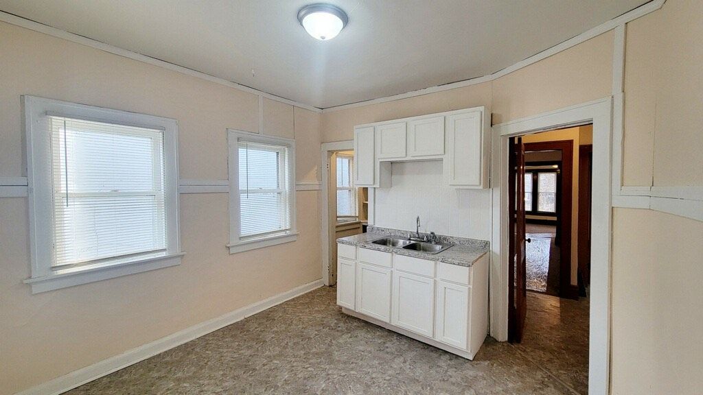 A kitchen with white cabinets and a sink in an empty room.