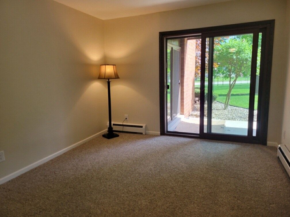 An empty living room with a sliding glass door and a lamp.