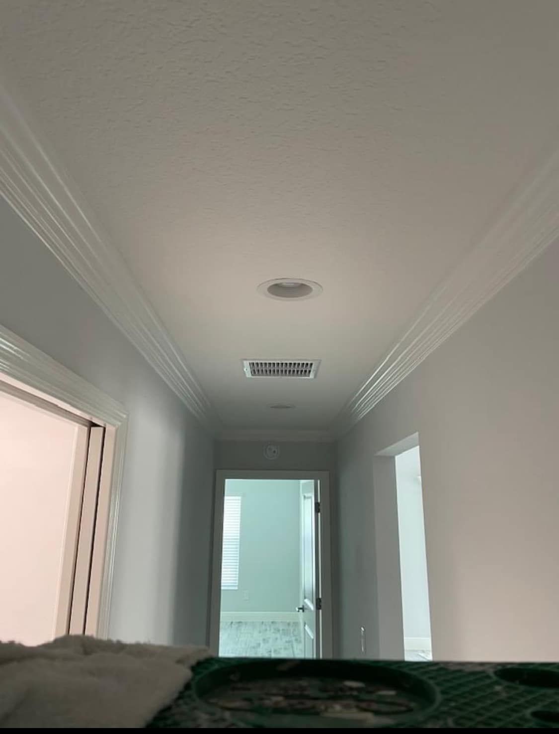 A long hallway with white walls and a ceiling fan